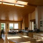 Kitchen with sitting area and fireplace beyond.  The great room is divided into four spaces of kitchen, eating area or nook, TV area and sitting area.  Due to the size of the room, a huge ridge skylight is included in the design which  provides comfortable light levels throughout the space.