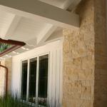 Large stone veneer pilaster with entry porch ceiling of custom rafter tails and siding beyond
