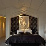 Master bedroom: Shallow bed alcove with custom headboard complements high-relief framed artwork.  Ceiling steps conceal roof framing beams.